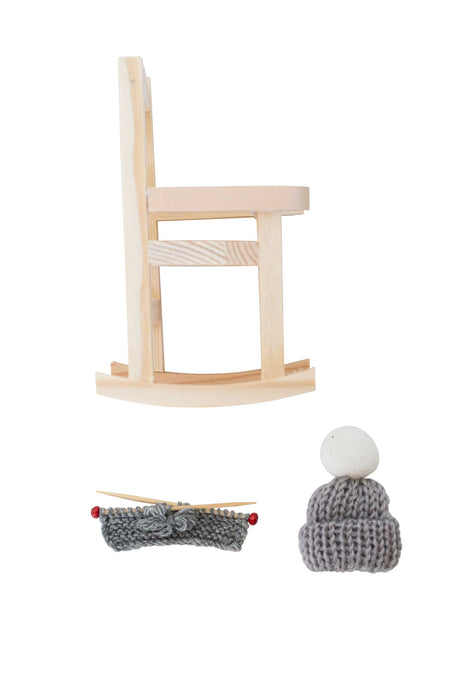 Gemütlicher kleiner Wichtel im Schaukelstuhl mit Strickset und Mützen als skandinavische Weihnachtsdekoration